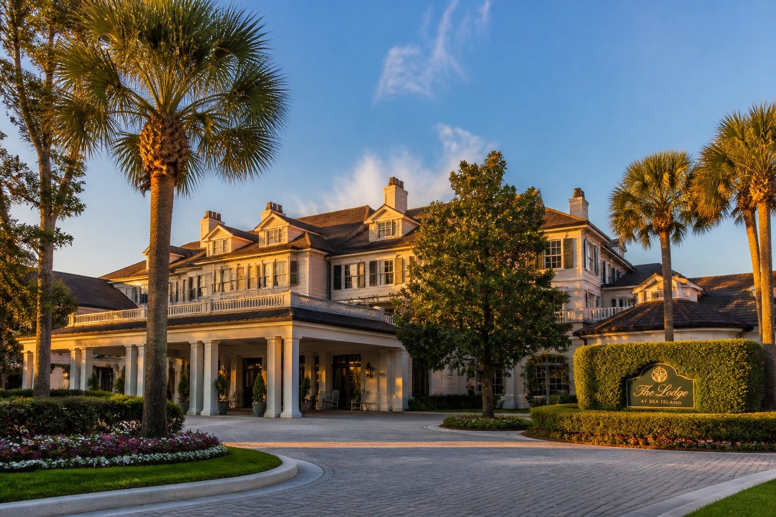 The exterior of a grand hotel surrounded by palm trees and manicured gardens under a clear sky.