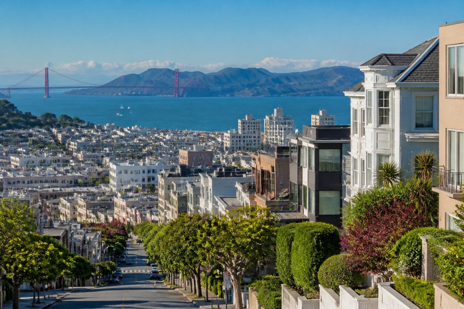 Panoramic view of upscale homes on rolling hills in Pacific Heights, San Francisco, with the San Francisco Bay and Golden Gate Bridge in the background.