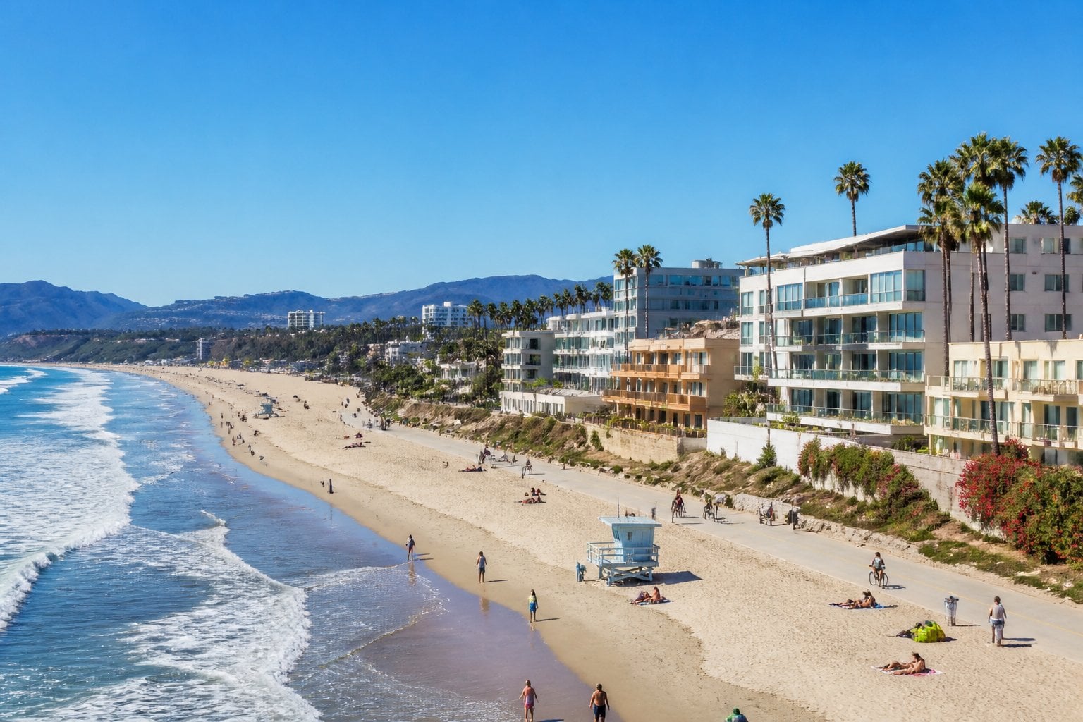 A sunny beach in Santa Monica, California with ocean waves, palm trees, and beachfront homes.