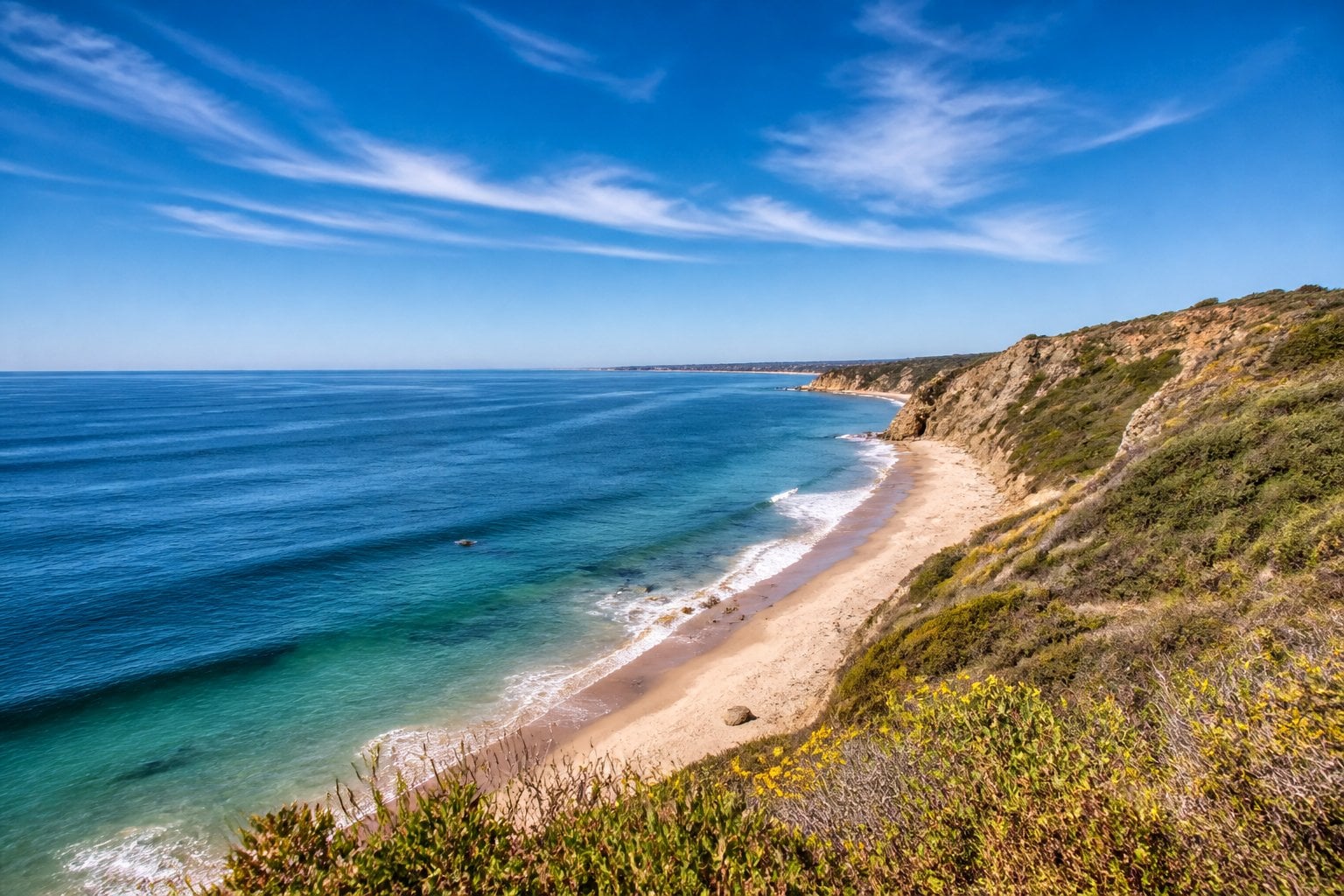 Cliffs and beach at Point Dume overlooking the Pacific Ocean under a clear sky.