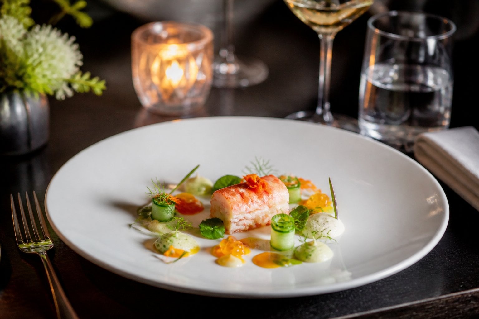 An exquisitely plated tasting-menu dish on a table in an upscale restaurant.